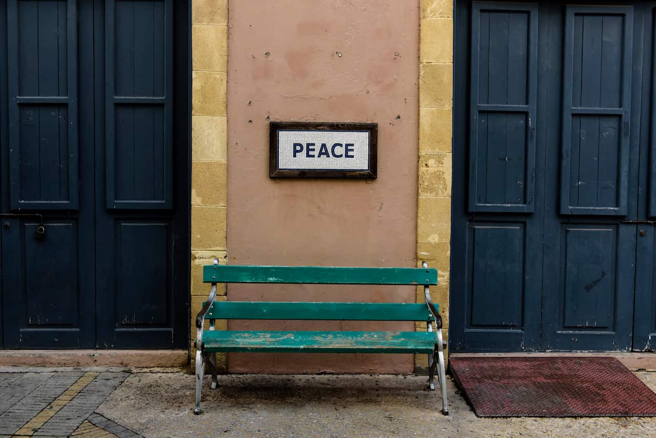 A bench with a placard on wall and text 'Peace', near the separation line between the two communities, Nicosia, the capital of Cyprus / EPA/Iakovos Hatzistavrou 