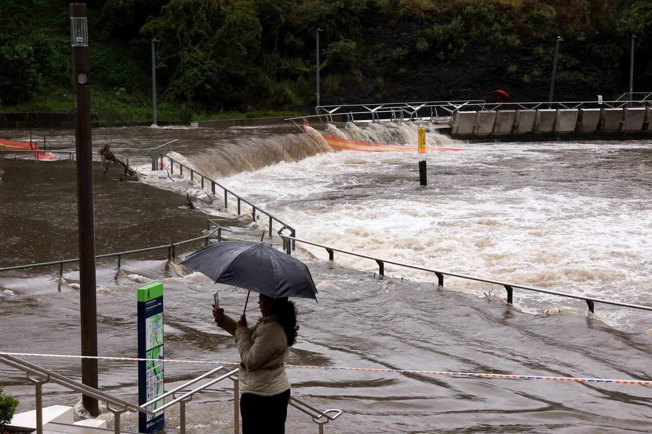 A woman taking a selfie while standing next to an overflowing river.