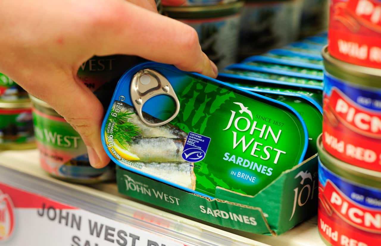 A person reaching for a can of sardines.