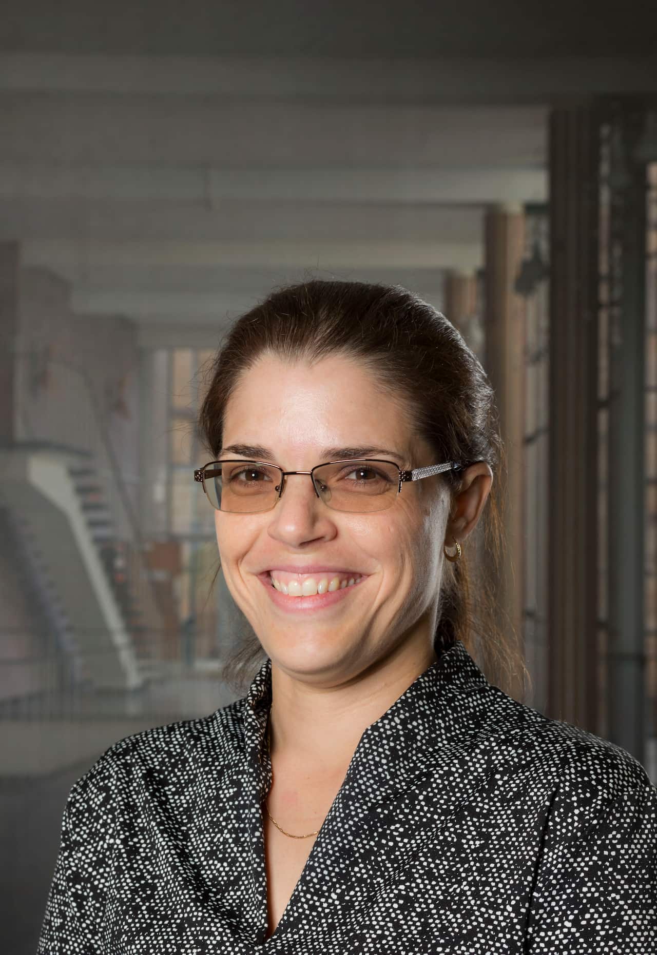 A woman wearing glasses and a black and white top smiles for the camera.