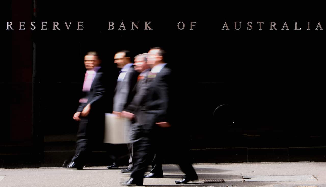 Four man in suits walking in front of the Reserve Bank of Australia