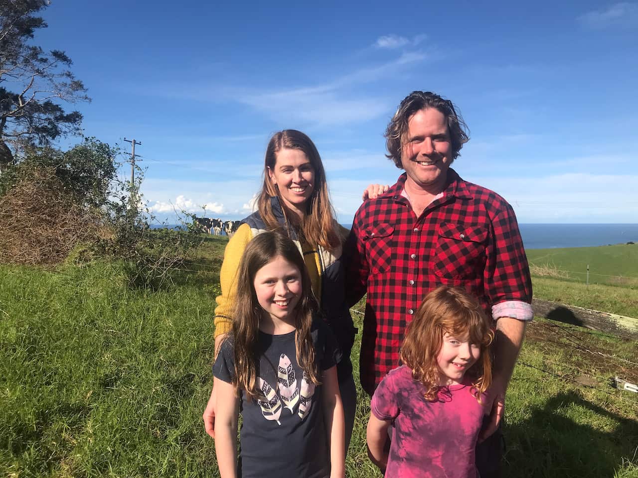 A man, a woman and two children standing on a farm