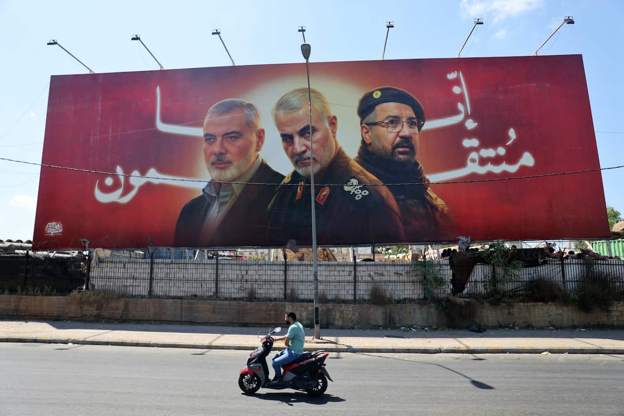 A billboard showing three figures superimposed in from of a glowing red background with Arabic writing on it.