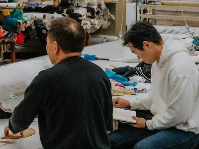 Two men sitting at a table in a textile factory