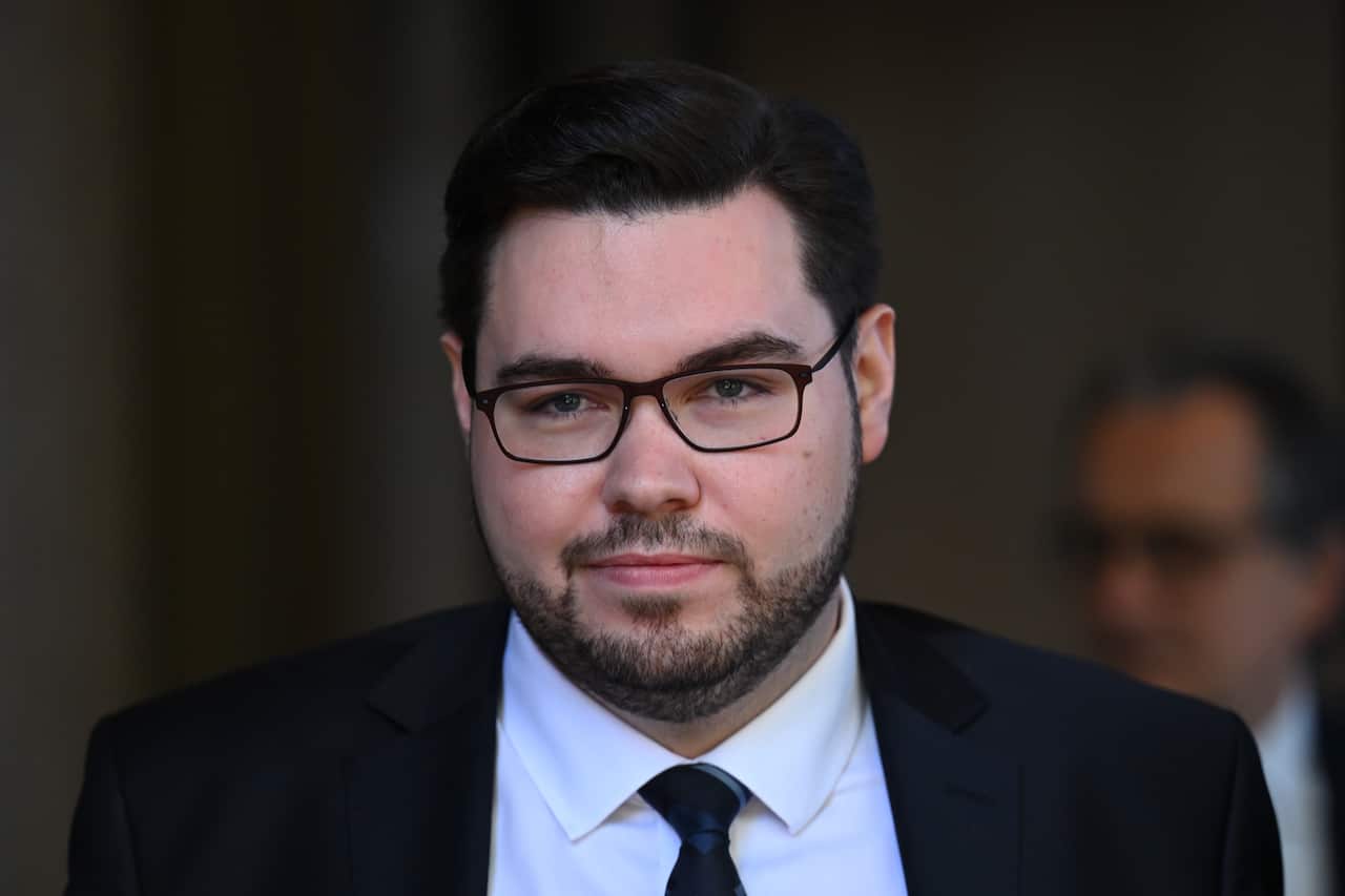 A man wearing a suit, tie and glasses walking.