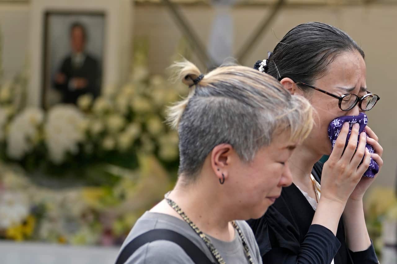 Two women cry at a memorial.