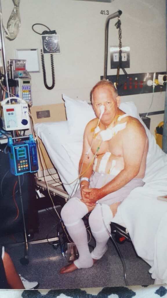 A man on a hospital bed with tubes and bandages 