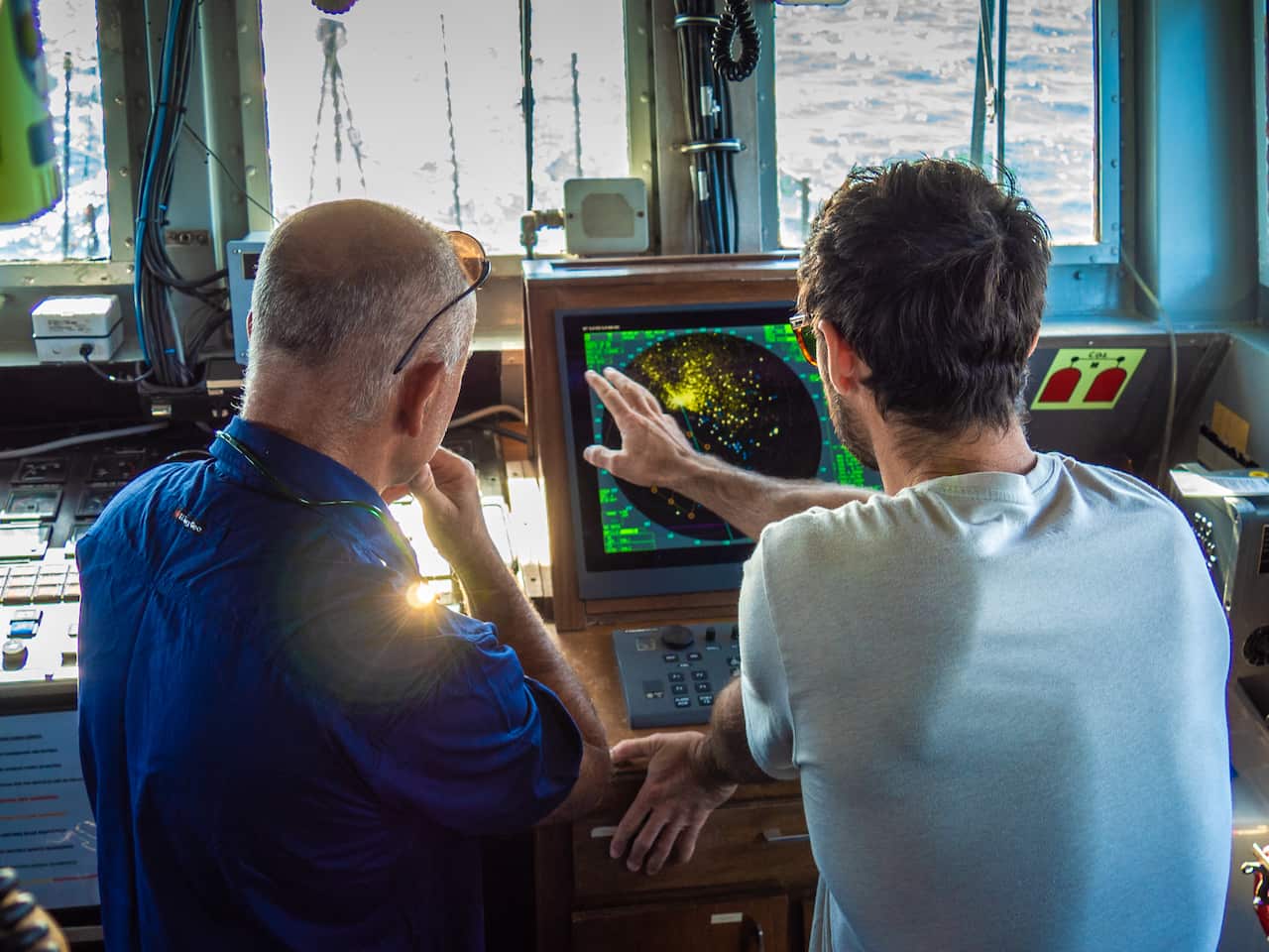 Two men look at a screen.