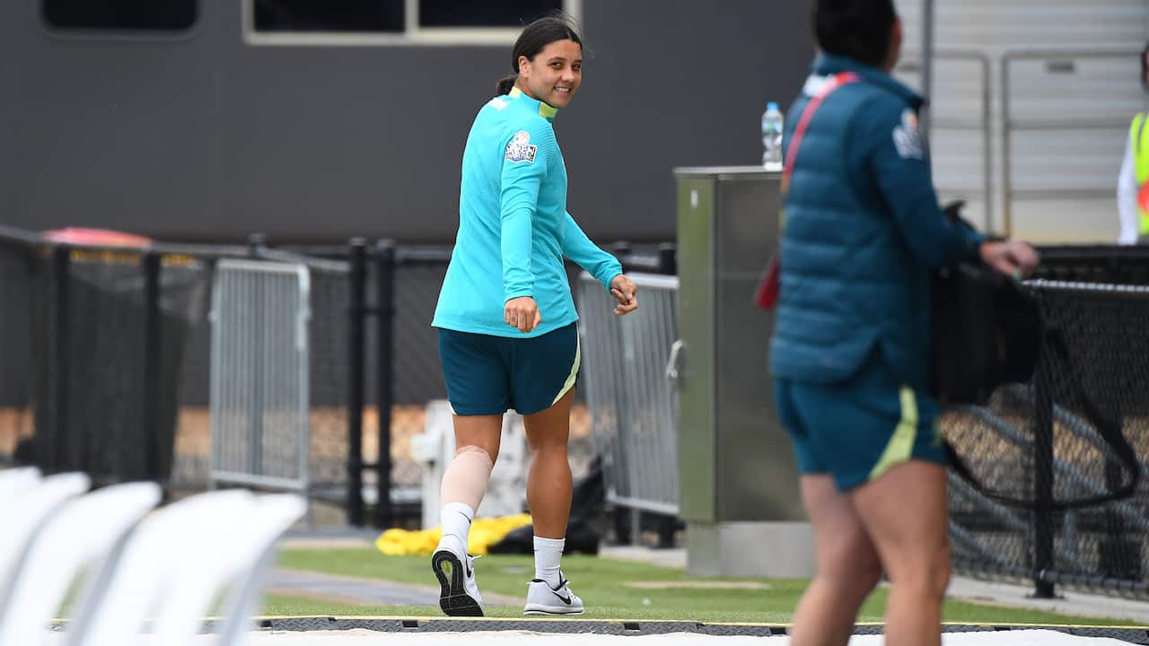 A woman in a green jacket looks over her shoulder to smile at the camera.