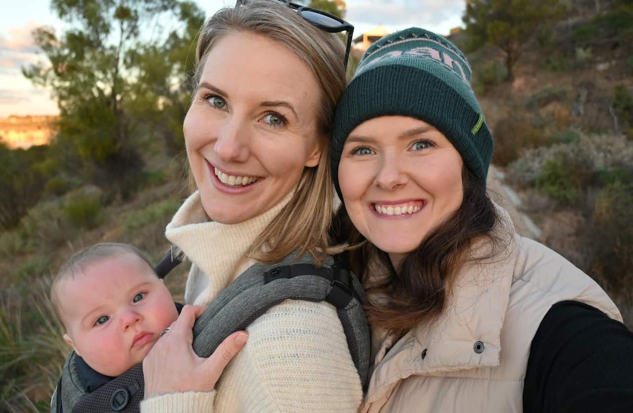 Two women and a baby standing outside