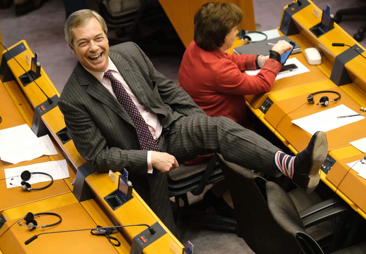 Nigel Farage smiles and shows his Union Jack socks in the European Parliament.