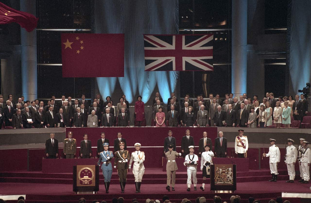 A Chinese and British flag are hung up on top of politicians and leaders in a ceremony on a podium