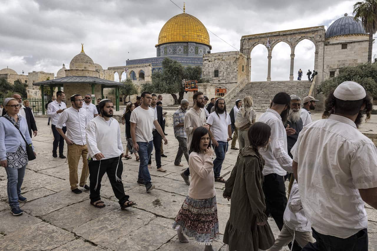 A group of religious Jewish men and women walk past the Dome of the Rock during their visit to the Temple Mount, which is known to Muslims as the Haram al-Sharif (The Noble Sanctuary), at the Aqsa mosques compound in the old city of Jerusalem on April 20, 2022. 