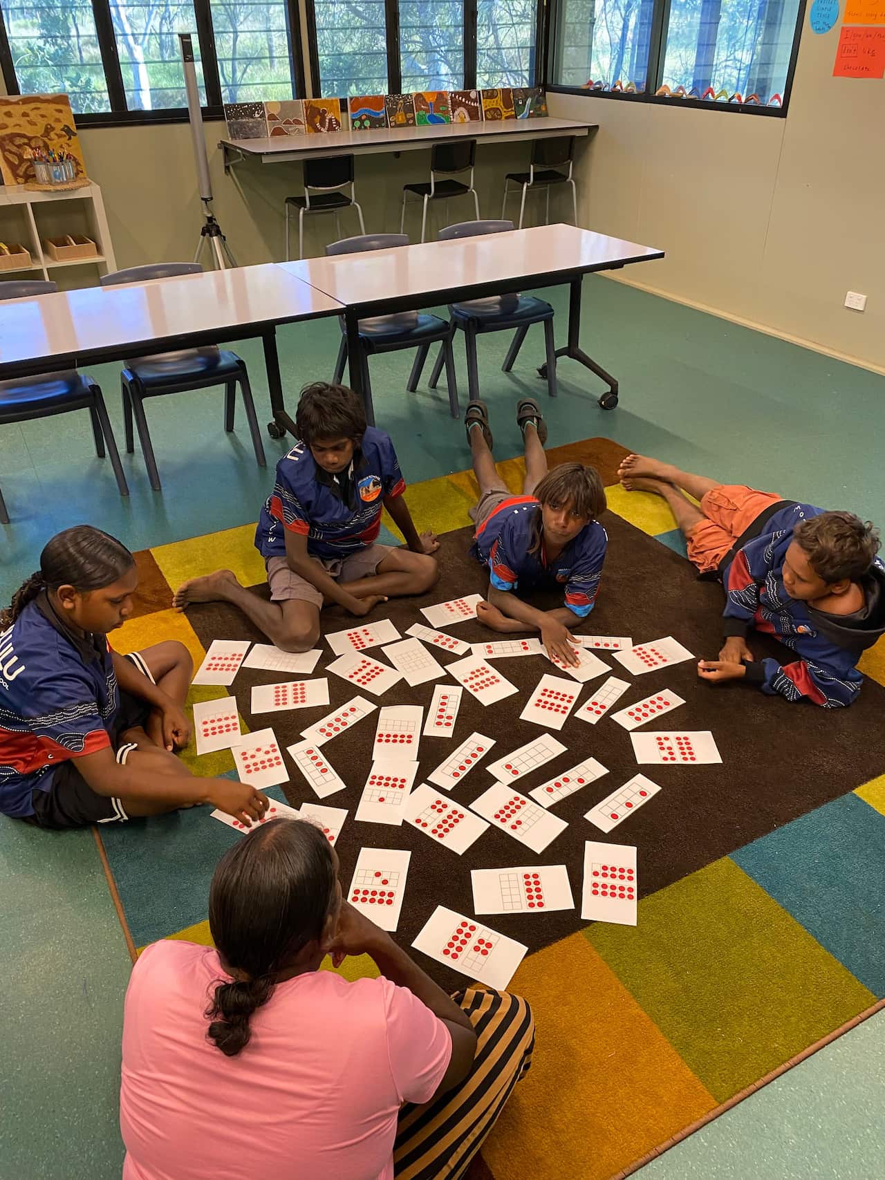 A group of children working with number sheets on the floor of a classroom