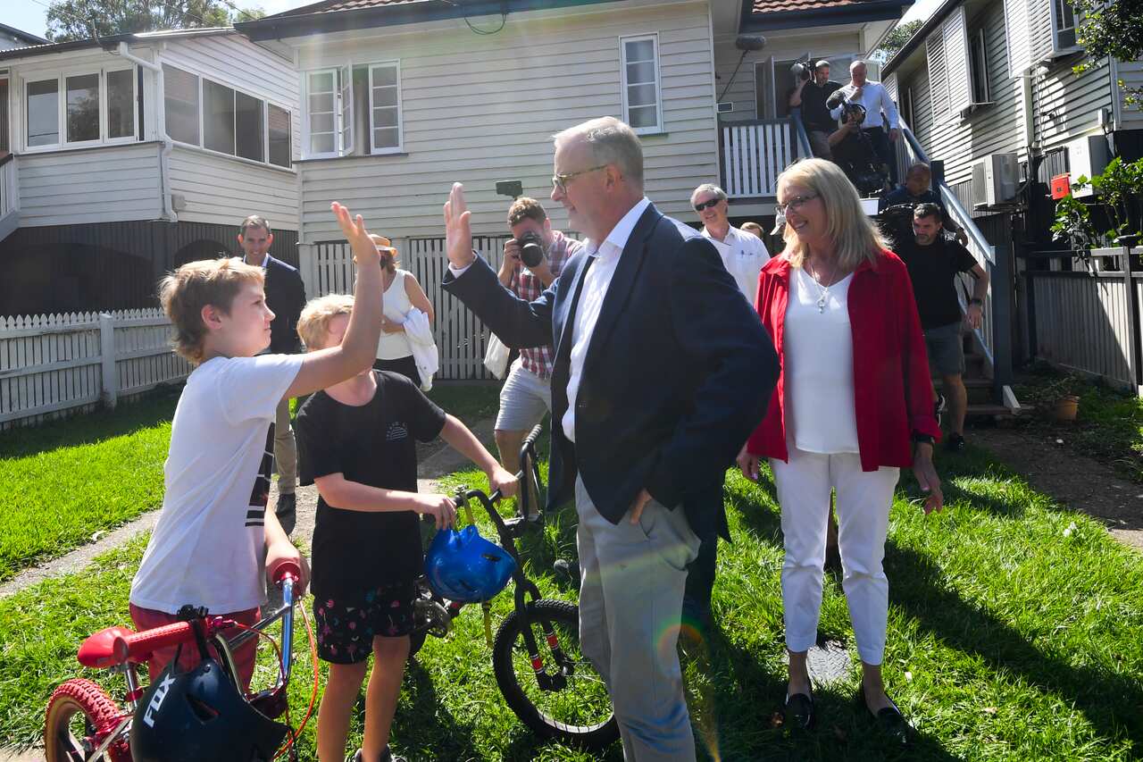 Anthony Albanese gives a 'high five' to a child in the front yard of a house in Brisbane.