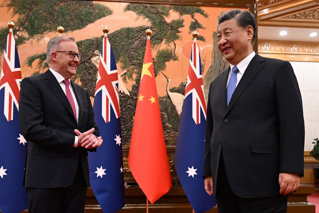 Anthony Albanese and Xi Jinping speak while standing in front of Chinese and Australian flags.