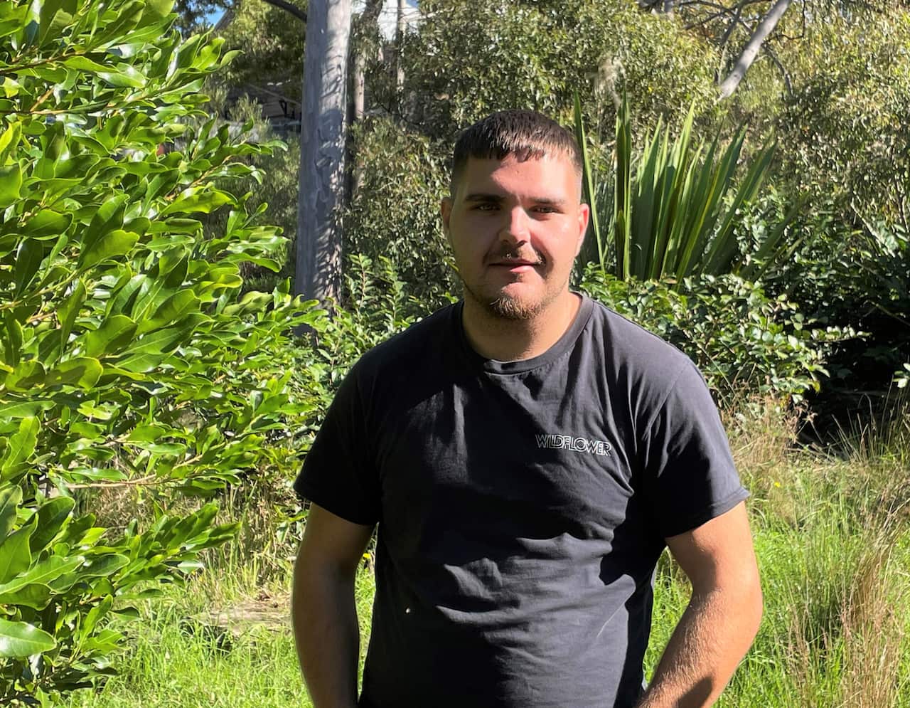 A man in a T-shirt standing in a native garden.