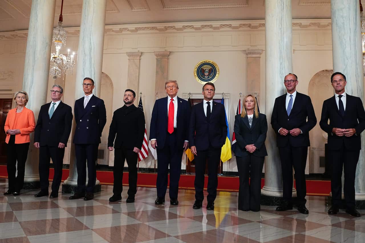 A group of people in business suits stand in a row posing for the camera.