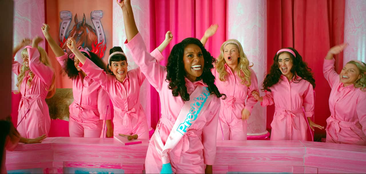 A scene from the Barbie movie with seven women in pink jumpsuits.