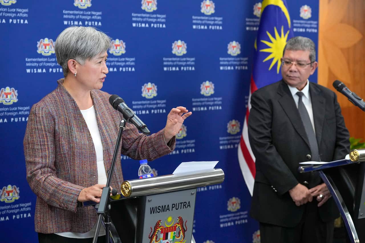 Australia's foreign minister at a podium alongside her Malaysian counterpart.