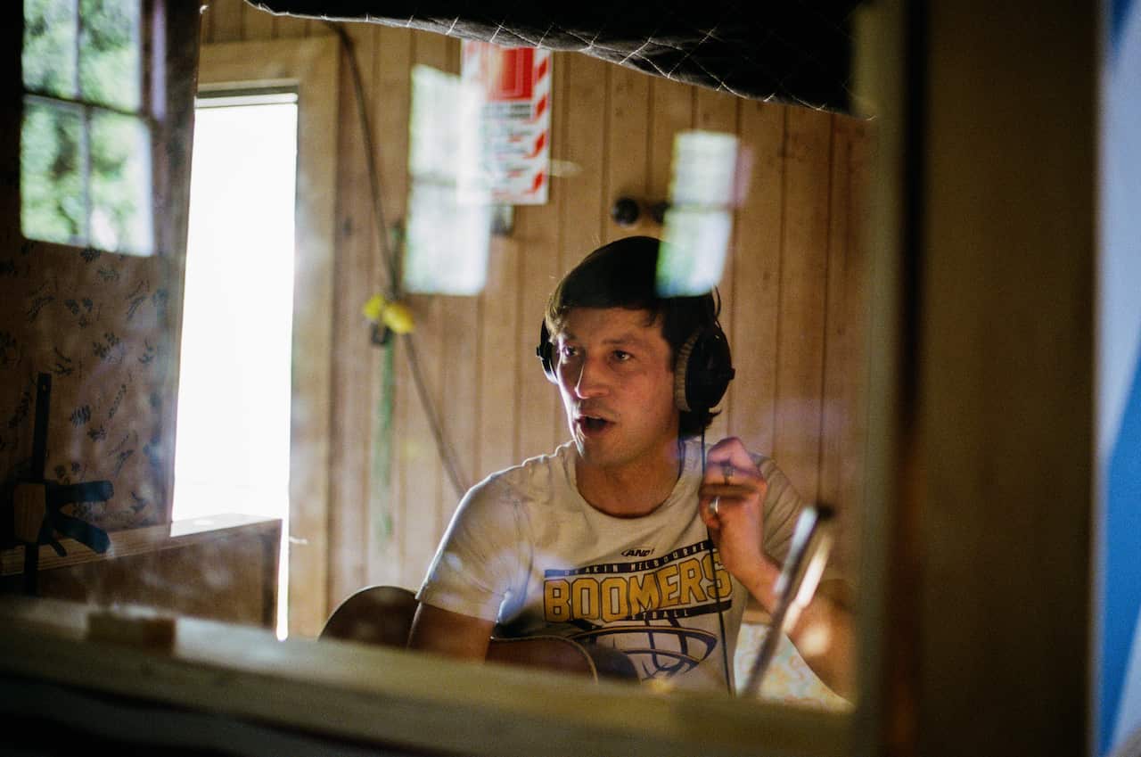 A man wearing headphones in a recording booth. 