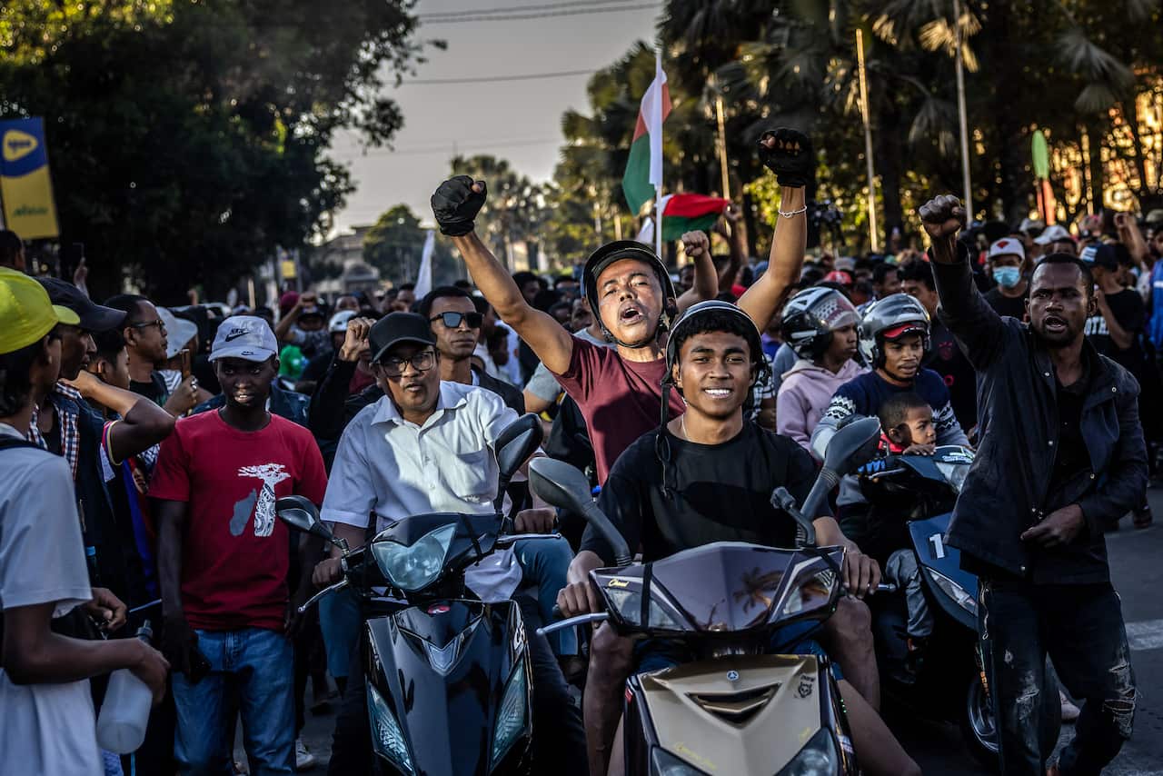 Motorcyclists drive, chanting anti-government slogans and waving Madagascar flags as they celebrate.