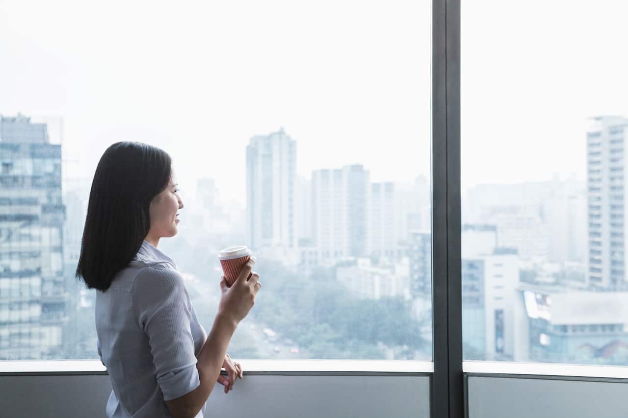 Businesswoman holding coffee cup and looking out the window
