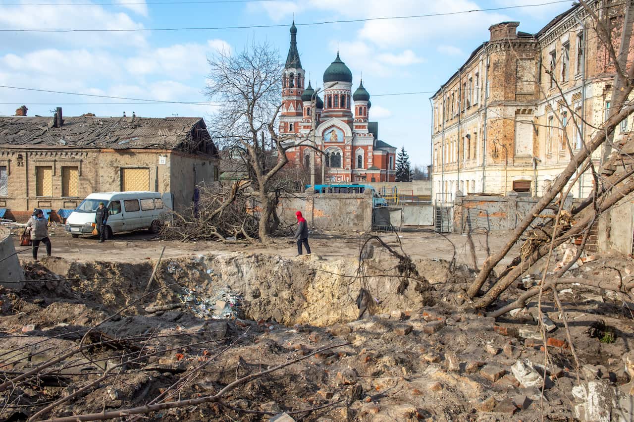 A woman is seen walking past a crater.