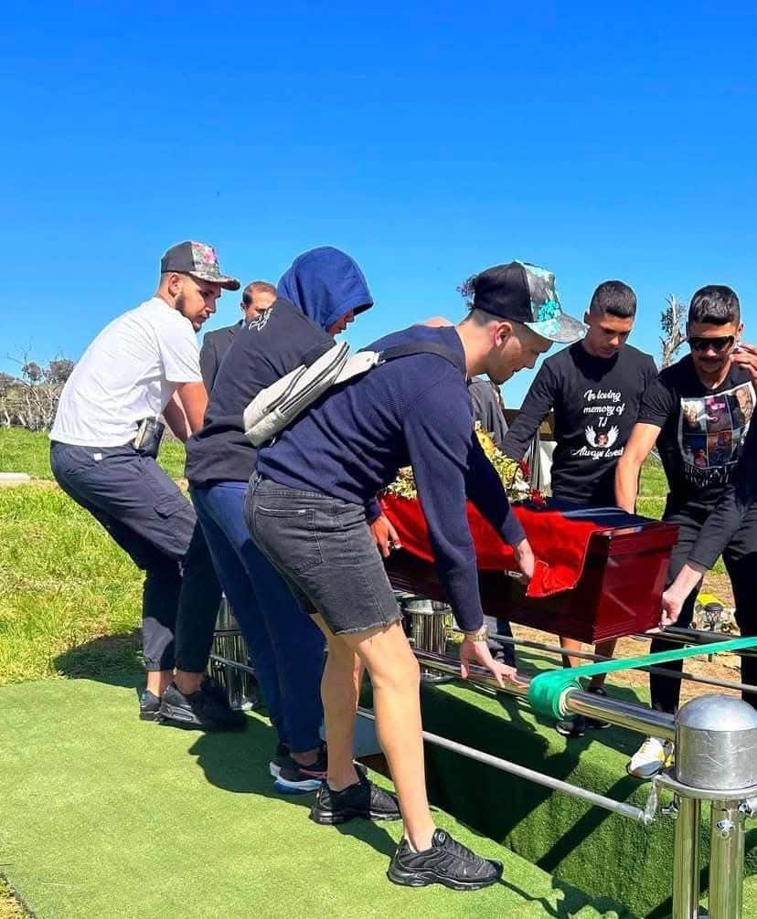 Several young men help to lower a coffin into cemetery plot.