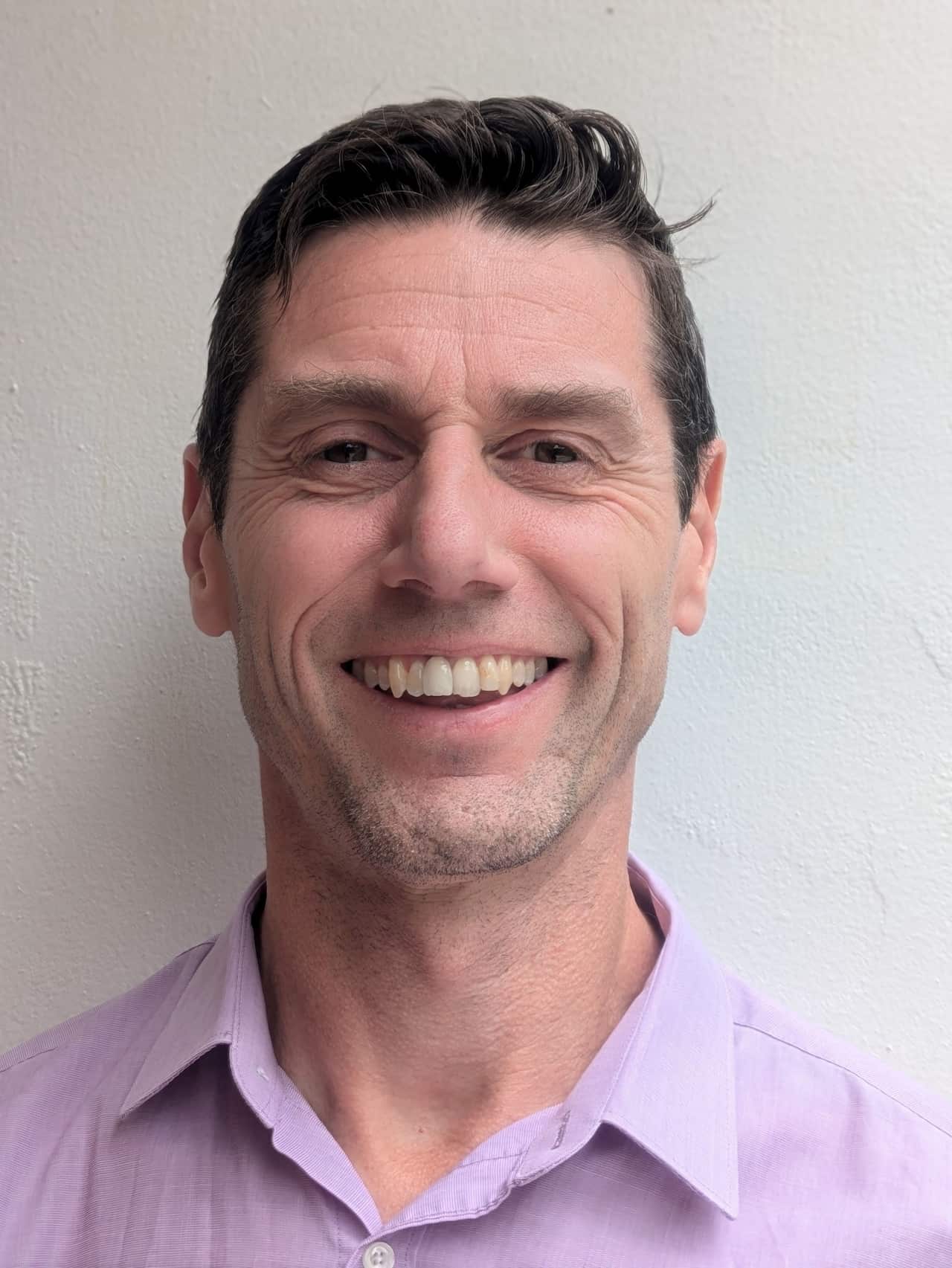 Close up of a smiling middle-aged man wearing a collared shirt.