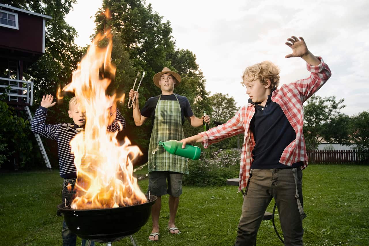 Boy pouring methylated spirit on barbecue fire