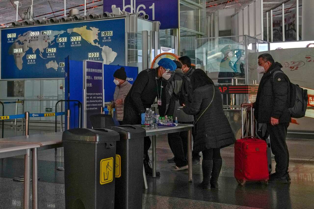 An officer checks the boarding pass of passengers going through the international departure gate at the Beijing Capital International Airport in Beijing on 29 December 2022.