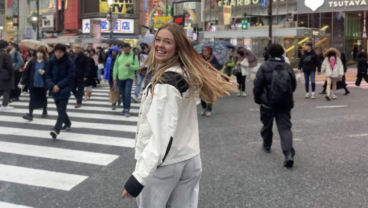 A young woman smiling as she walks through a crossing in Japan.