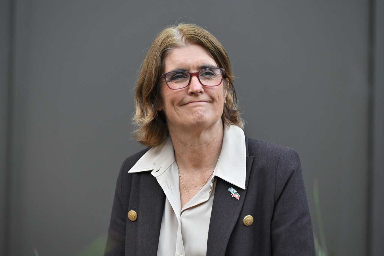 A woman with brown hear wearing glasses and a suit