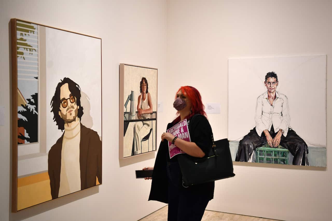 A woman looks at three paintings in an art gallery.