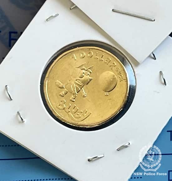 A gold coin featuring a picture of a cartoon dog catching a balloon. It is labelled "A dollarbuck: Bluey"
