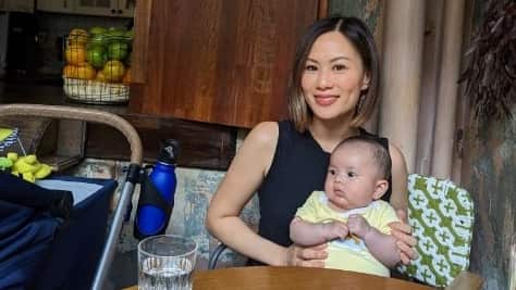 Woman sitting at a table holding a baby.