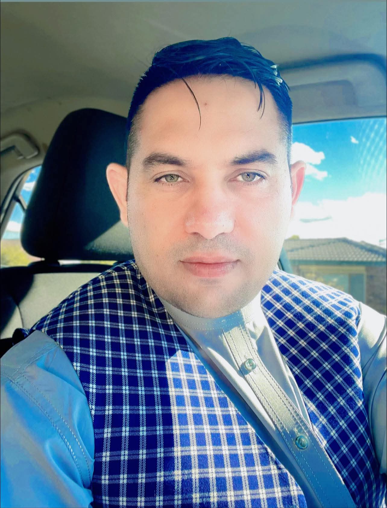 A man in a car wearing Afghan traditional men's clothing