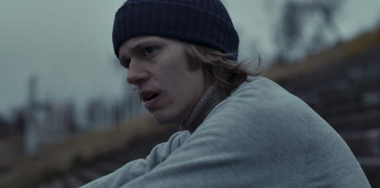 A man sits with sweats and a beanie on