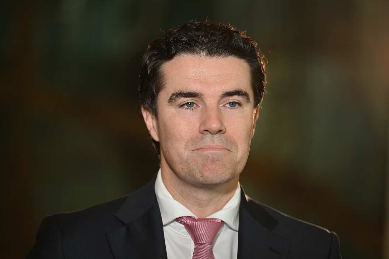 Tim Watts wearing a dark blazer and pink tie.