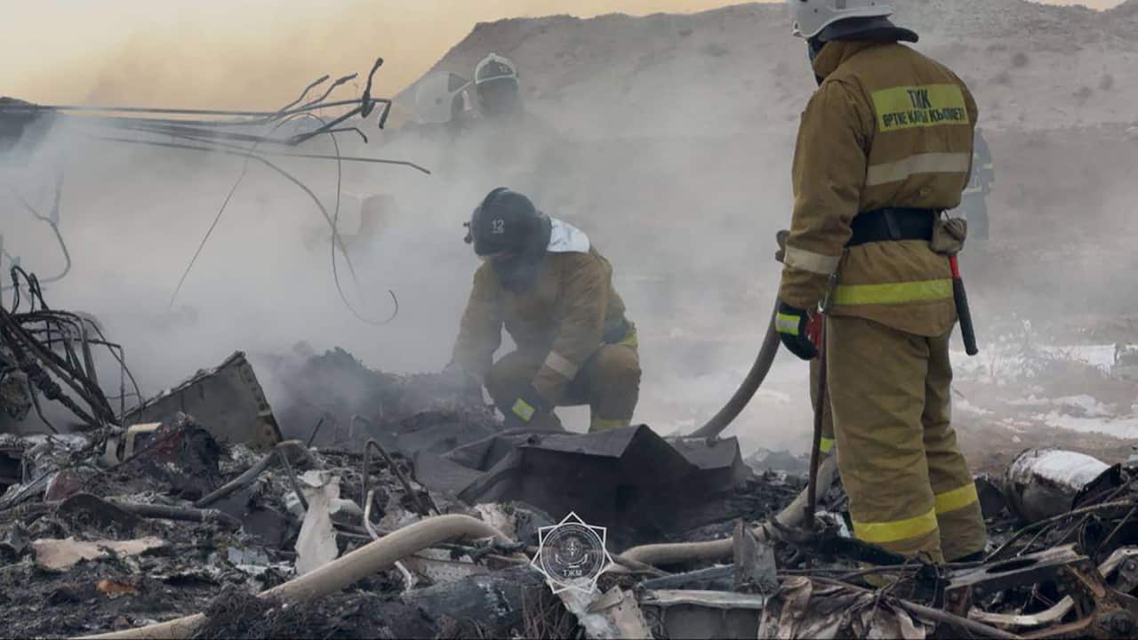 Emergency specialists inspecting plane wreckage at a crash site.