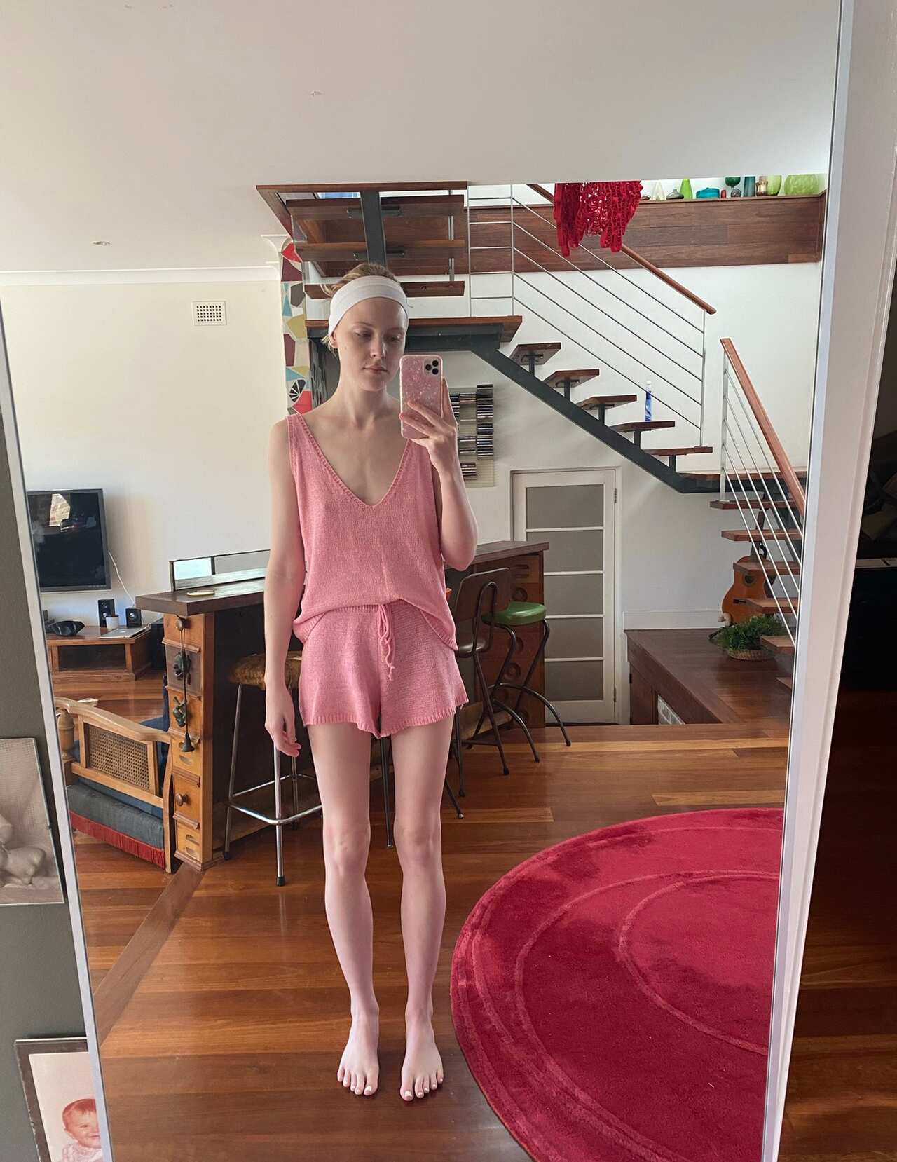 A young woman taking a photo of herself in the mirror