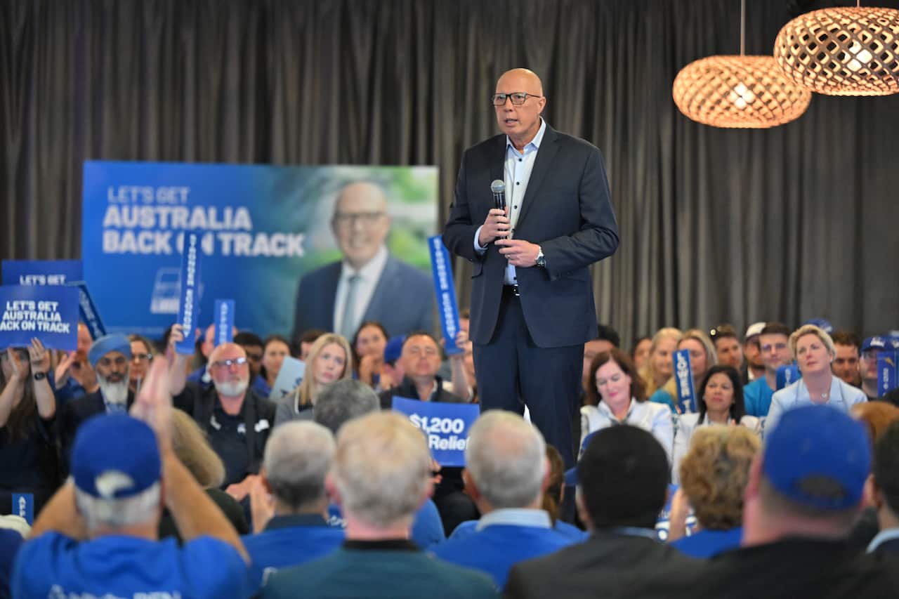 Peter Dutton stands on a stage surrounded by supporters. 
