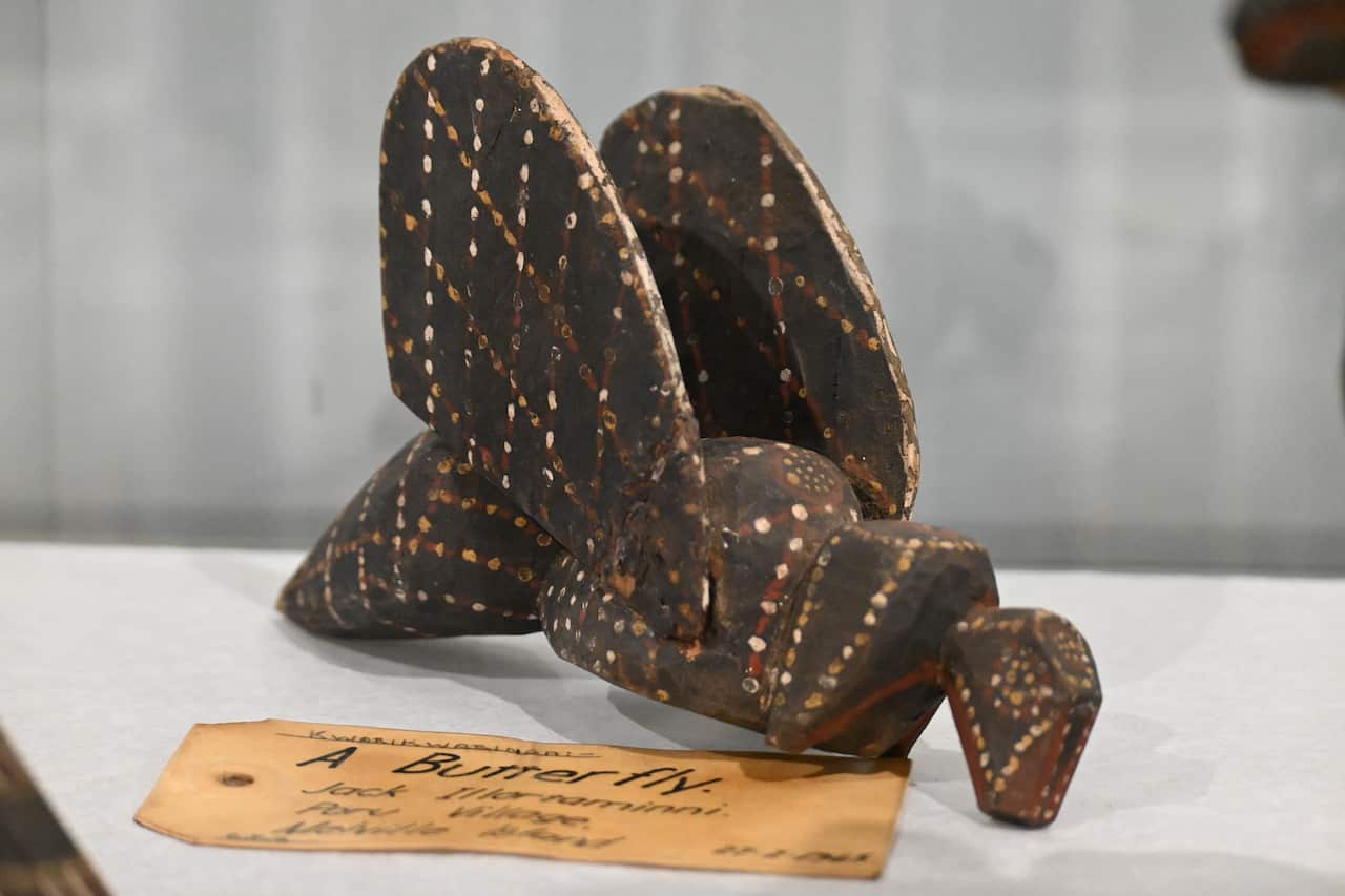 A wooden butterfly with a label next to it