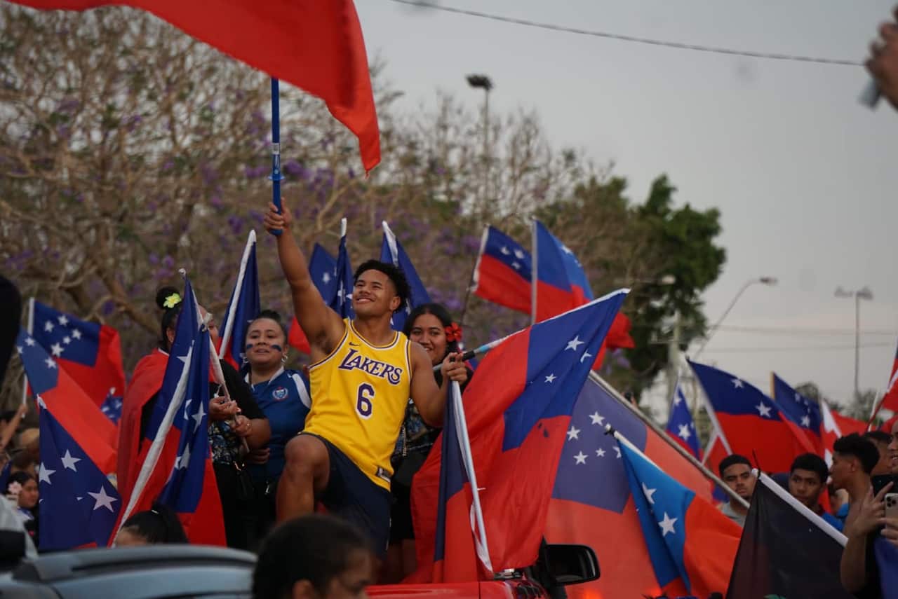 People hold up Samoan flags. 