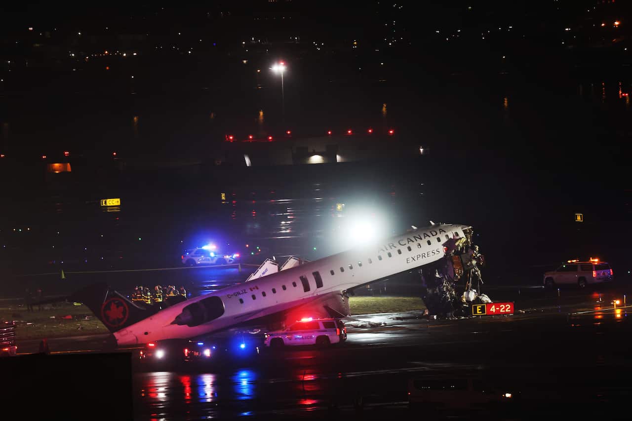 Air Canada Express plane surrounded by emergency vehicles on the tarmac.