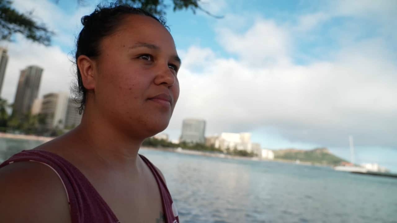 Hawaiian woman Makana Kāne Kuahiwinui looks out to sea watching the surf break
