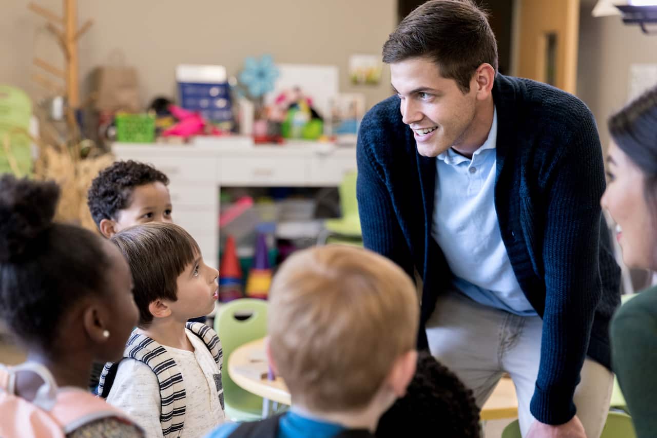 Male teacher talks to attentive kindergarten class