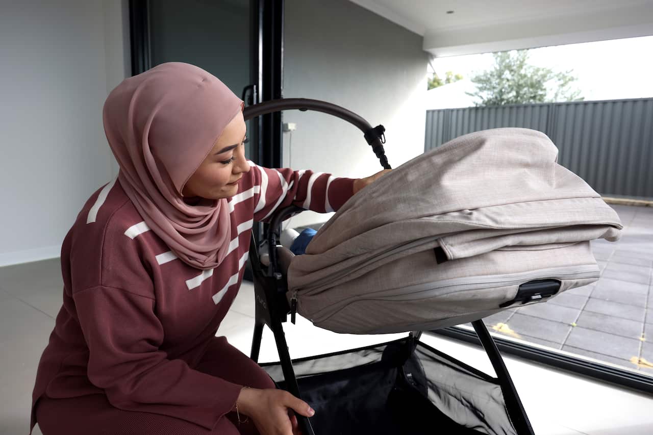 Fatima Payman tends to her daughter, who lies in a stroller in a family room.