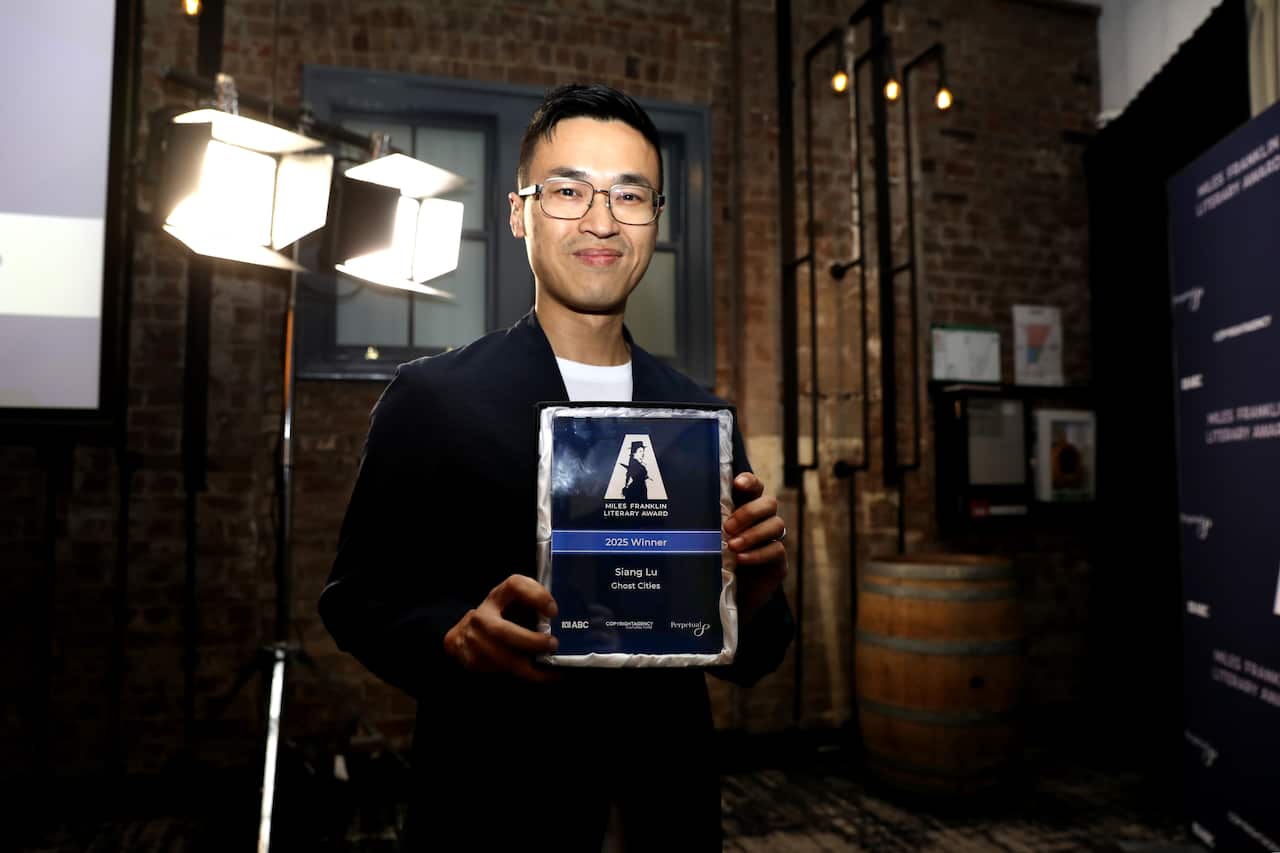 A man holding an award frame and smiling.